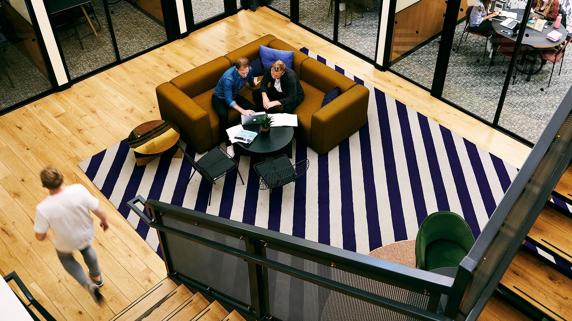 A casual meeting taking place on a sofa whilst a person walks past